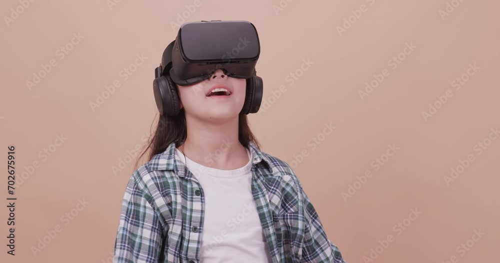 A girl having fun with game while wearing virtual reality glasses. Isolated on brown background in studio. A girl having fun with game while wearing virtual reality glasses. Isolated on brown background in studio.