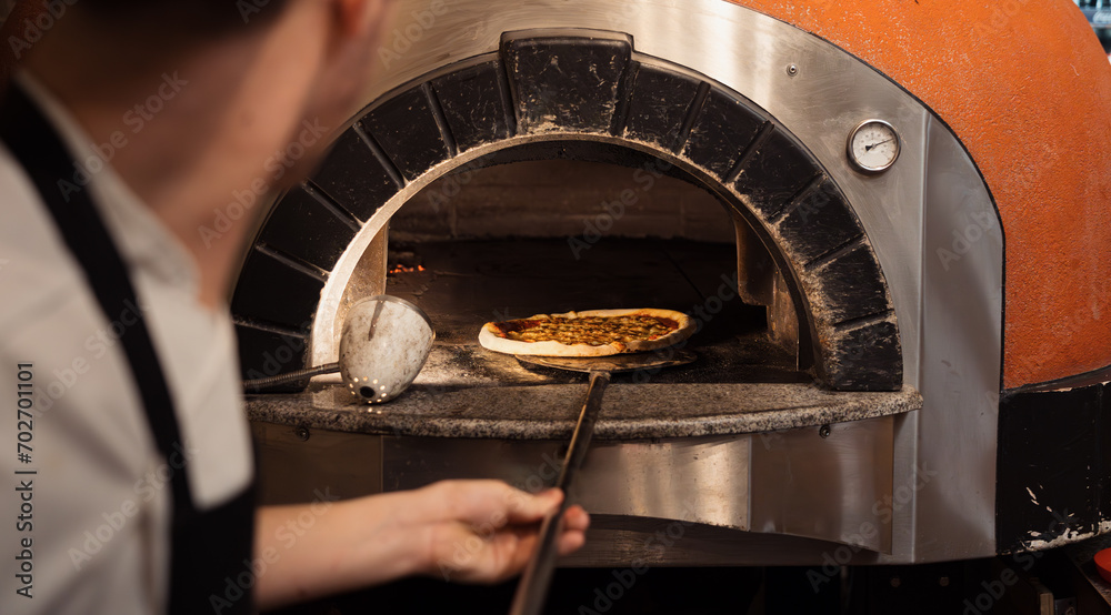 Foto de A chef skillfully slides a pizza into a woodfired oven