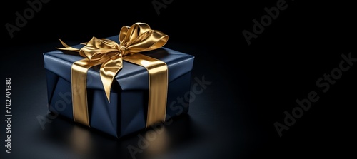 Black box with gold ribbon on black background with copy space