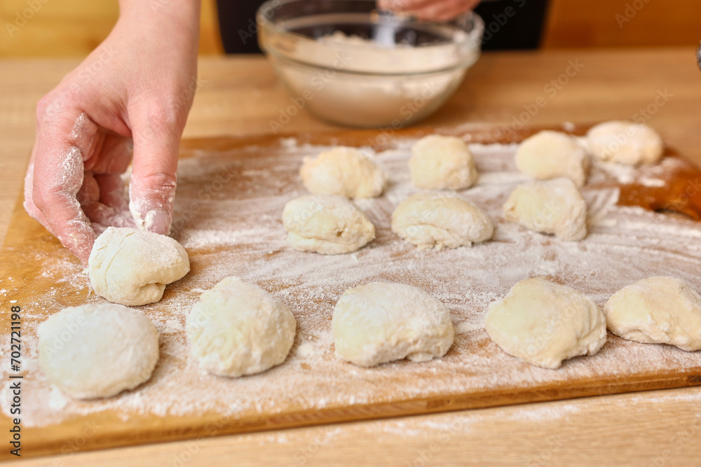 A woman forms pieces of dough for making donuts. The process of making donuts A woman forms pieces of dough for making donuts. The process of making donuts