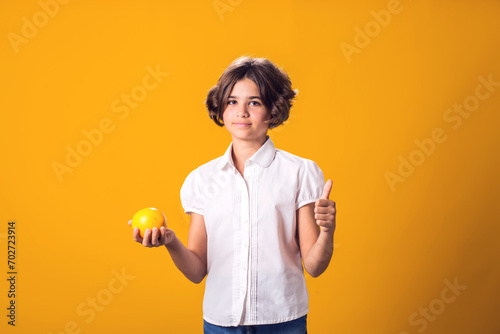 Girl holds an oranges in hand and shows thumbs up gesture. Healthy food and children nutrition concept © Aleksej