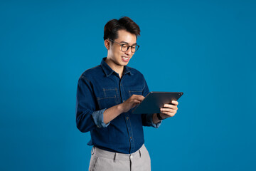 Portrait of young Asian business man posing on blue background