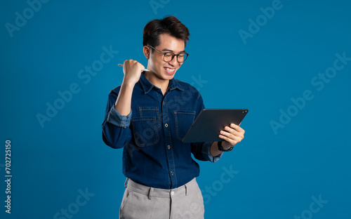 Portrait of young Asian business man posing on blue background