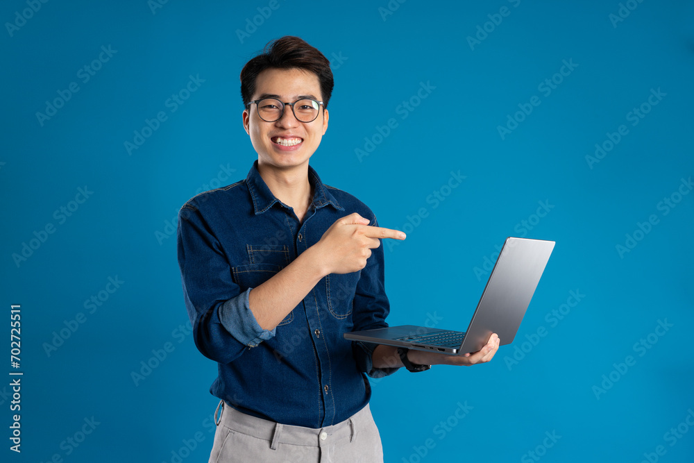 Portrait of young Asian business man posing on blue background Portrait of young Asian business man posing on blue background