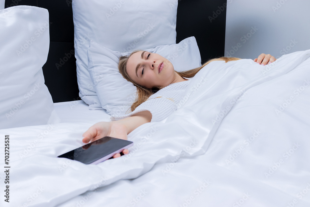 Young blond woman fell asleep with smartphone in hand. Chatting, checking social media, reading news before sleep. Mobile addict concept. Young blond woman fell asleep with smartphone in hand. Chatting, checking social media, reading news before sleep. Mobile addict concept.