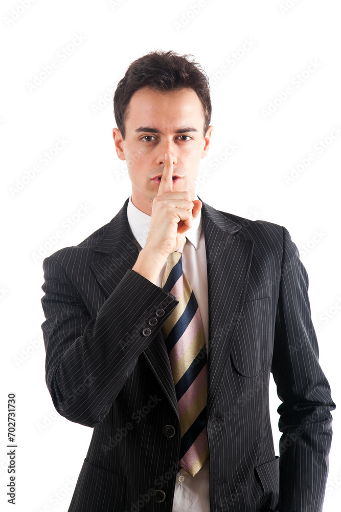 Young professional man in suit making a silence sign against a w Young professional man in suit making a silence sign against a w
