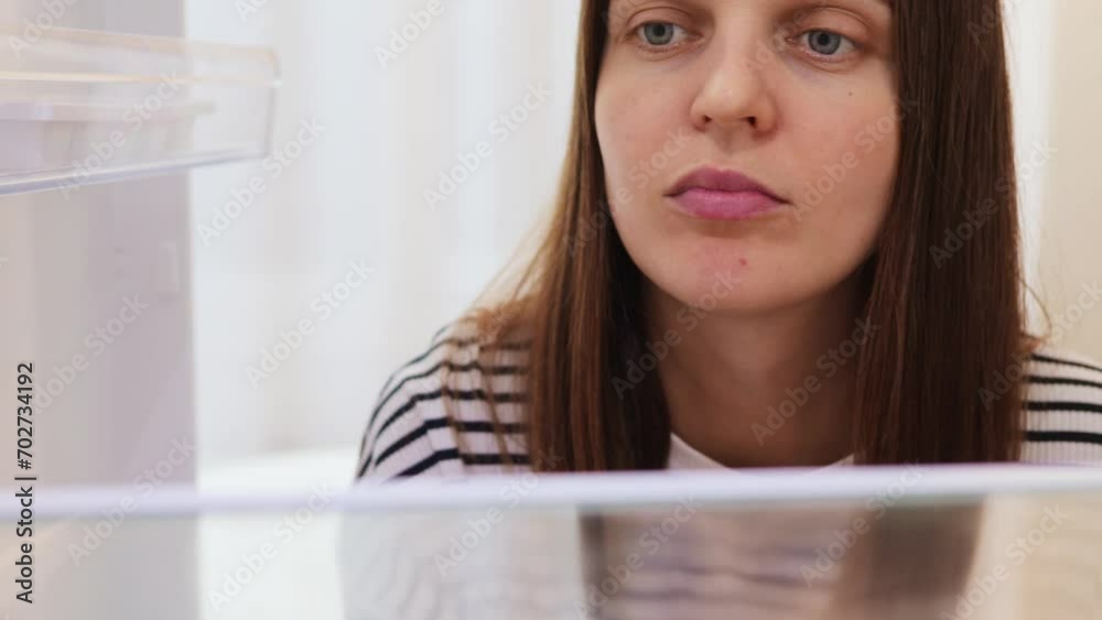 View from inside of fridge of beautiful brown haired adult girl holding oranges and putting it in refrigerator standing near the open fridge in kitchen View from inside of fridge of beautiful brown haired adult girl holding oranges and putting it in refrigerator standing near the open fridge in kitchen