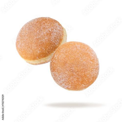 Two fresh baked donut sprinkled with sugar powder flying isolated on white background. Sweet doughnut closeup. Berliner donuts.