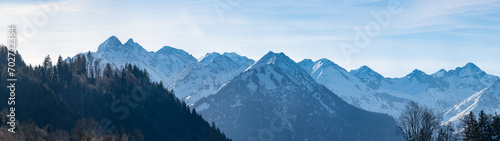 Panorama view landscape background of mountains with snow and forest trees in winter in in the Allgäu alps photo