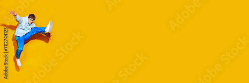 Young attractive man, dressed in comfy sportwear jumping in motion against vivid yellow background with negative space for text. Concept of fashion and beauty, modern style, shopping, sales. photo