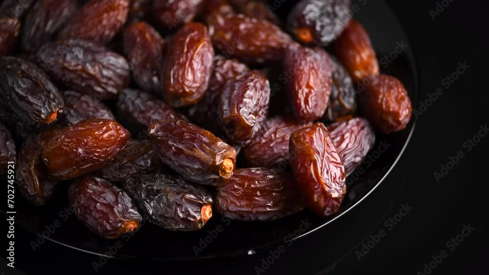 Dates fruit. Date fruits rotating on black background. Big plate full of Medjool dates close up. Tasty healthy Food Dates fruit. Date fruits rotating on black background. Big plate full of Medjool dates close up. Tasty healthy Food