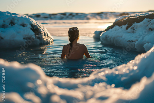 Woman ice bathing through a hole in the ice on a frozen lake, a health and wellness practice.