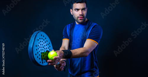 Padel tennis player with racket. Man athlete with paddle racket on black background. Sport concept. Download a high quality photo for sports website. © Mike Orlov