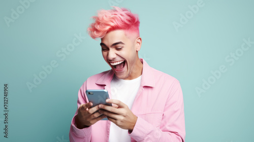 A pink-haired young man looking at the smartphone and laughing closeup.