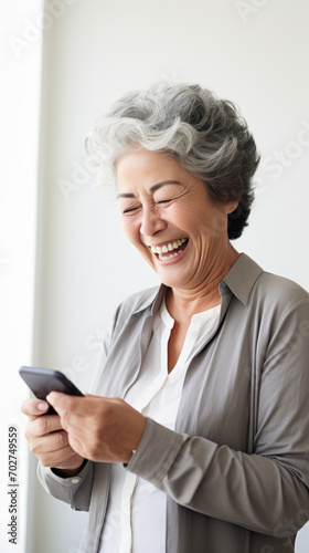 A senior woman looking at the smartphone and laughing closeup.