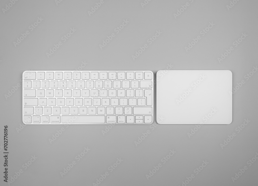 Top view of white keyboard, touchpad on light grey background. Modern office flat lay, copy space. Top view of white keyboard, touchpad on light grey background. Modern office flat lay, copy space.