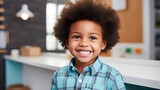 An African-American preschool boy looks at the camera with a smile while standing in a dental office while being examined by a dentist. Pediatric dentistry and primary dental care for dental health