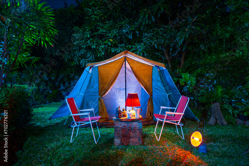 vintage cabin tent, Antique oil lamp, retro chairs, Group of camping tents with outdoor coffee-making facilities on wooden tables in a forest camping area at night in the forest