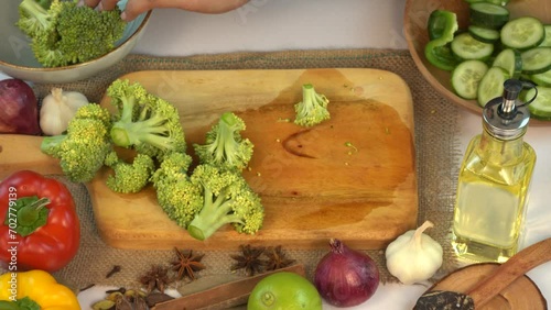 Woman's hands using kitchen knife to chop vegetables including broccoli