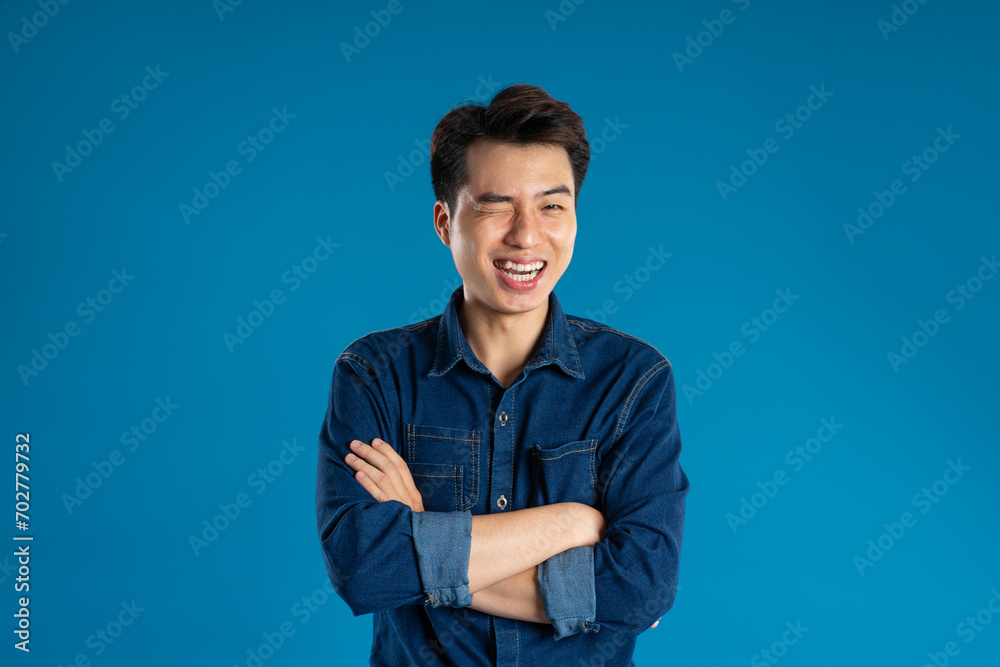 Portrait of young Asian business man posing on blue background Portrait of young Asian business man posing on blue background