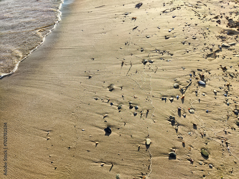 Yellow sand, pebbles and a transparent wave as a background, texture. Abstract pattern, place for text, copy space Yellow sand, pebbles and a transparent wave as a background, texture. Abstract pattern, place for text, copy space
