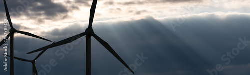 Silhouette wind turbines against cloluds. Dark clouds and sun beams in the evening. Renewable and sustainable energy, climate change, technology. 3D illustration photo