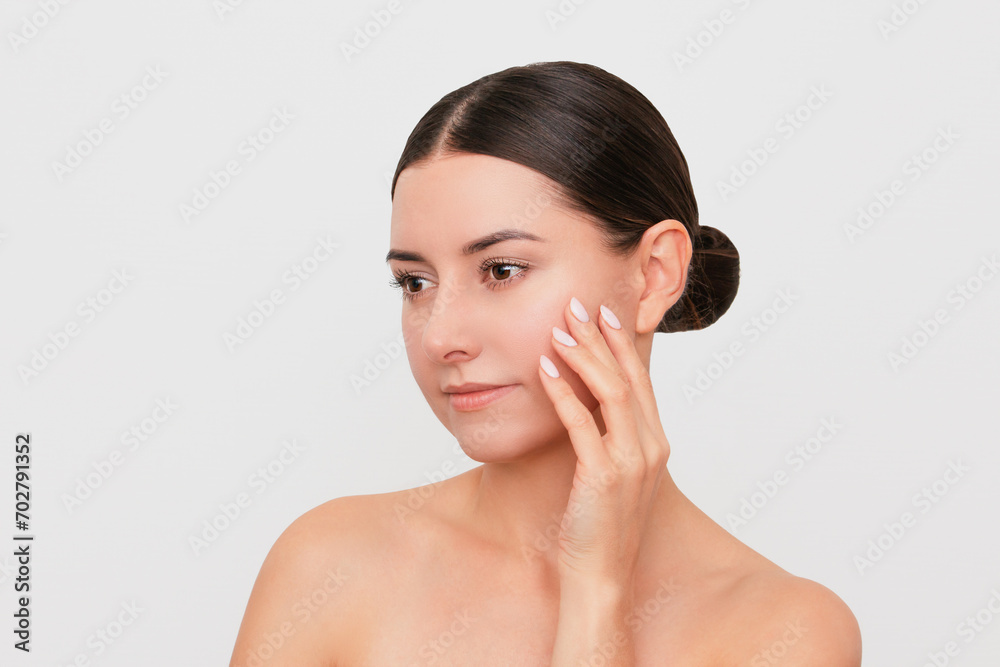 Profile of a young naked beautiful Caucasian dark-haired woman touching her face with her hand and enjoying clean and beautiful skin. Isolated on a light background Profile of a young naked beautiful Caucasian dark-haired woman touching her face with her hand and enjoying clean and beautiful skin. Isolated on a light background