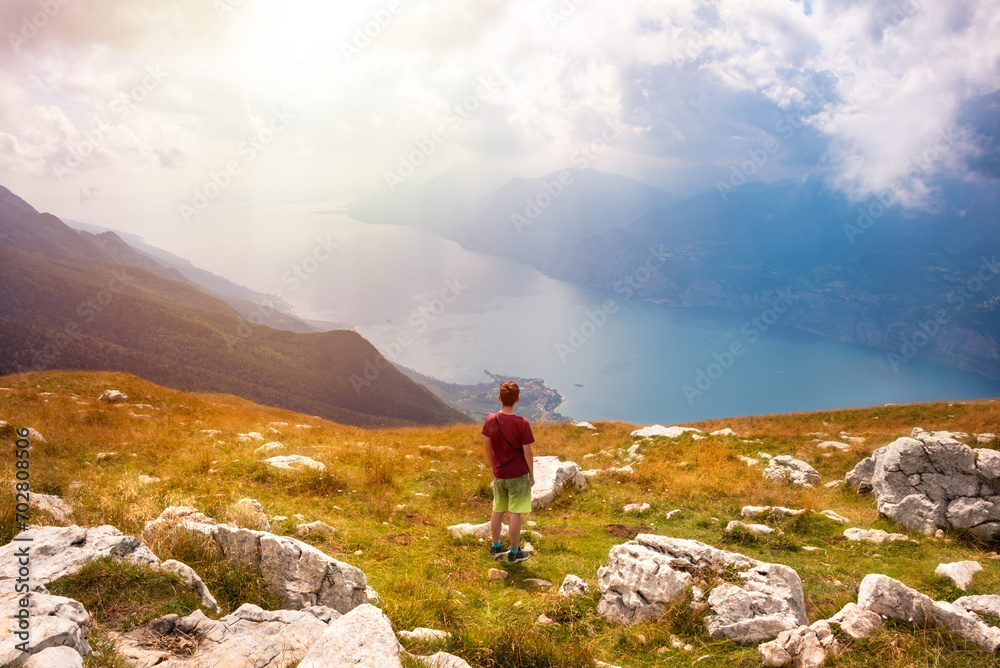 Hiker looking at panoramic view of lake Garda from a mountain