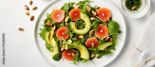 Vegan salad with arugula, avocado, grapefruit, cashews, olive oil-honey dressing, on white table top view.