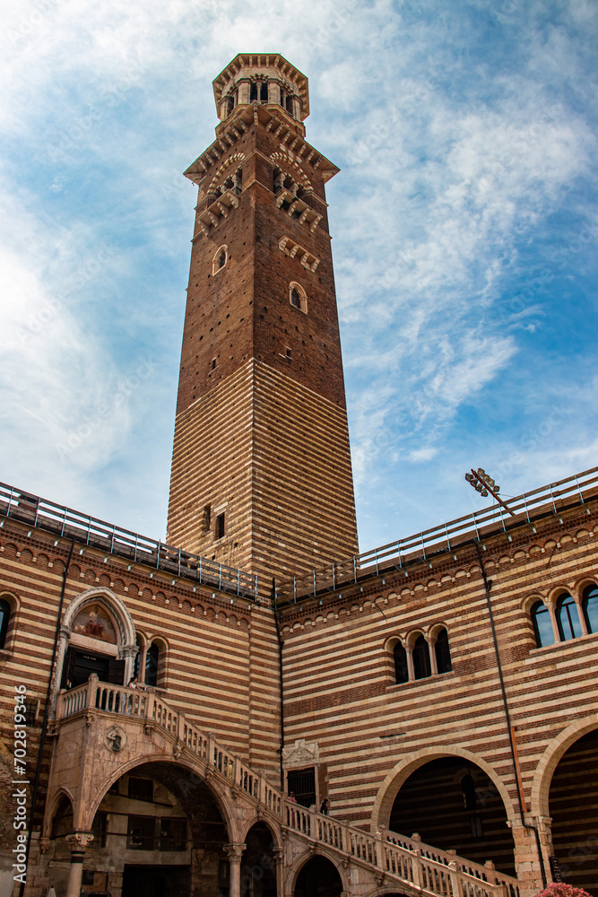 Medieval Lamberti (Torre dei Lamberti) tower XI century with clock, 84 metre and antica ancient column (1400 a.D) on Erbe Square in Verona city.