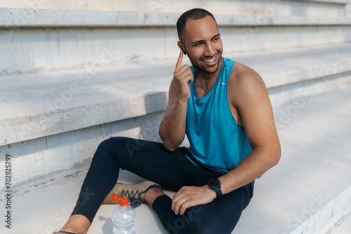 Smiling young man fixing an earphone in his ear