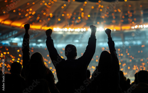 Silhouettes of cheering crowd in front of a large football stadium photo