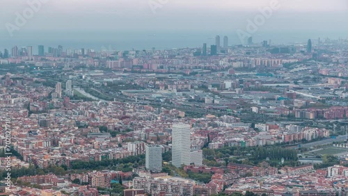 Evening Timelapse of Barcelona and Badalona Skylines. Aerial View from Iberic Puig Castellar Village Viewpoint, Spectacular Panorama with Roofs of Houses, a Meandering River and Vast Sea on Horizon photo