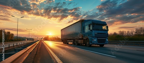 Industrial Long hauler big rig blue semi truck tractor with extended cab for truck driver rest transporting frozen cargo in refrigerator semi trailer driving on the highway road at sunset twili © vxnaghiyev