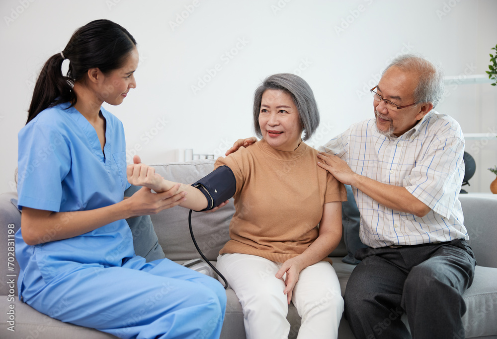Obraz premium caregiver or nurse measure blood pressure to senior woman on sofa