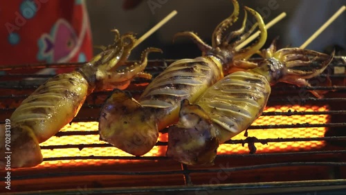 Fresh Squid on skewers is being grilled by a street vendor in Thai street night market, Thai style food.