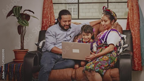 Hispanic family on the sofa in their living room .
Mayan indigenous family in a rural area use technology to educate their little girl. photo