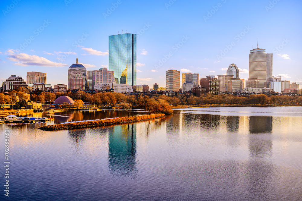 Obraz premium Boston City Skyline over the Charles River in Massachusetts, USA. A tranquil riverscape of Back Bay with golden illuminated wintery foliage in New England.