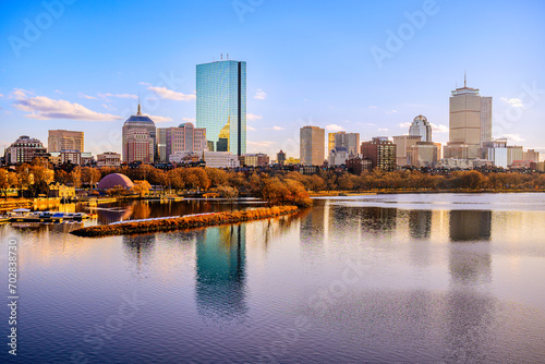 Boston City Skyline over the Charles River in Massachusetts, USA. A tranquil riverscape of Back Bay with golden illuminated wintery foliage in New England.