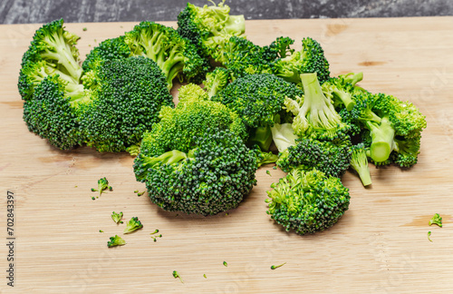 Fresh green broccoli divided into florets on wooden board. Appetizing vegetable for a healthy diet.