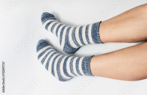 Side view of legs in socks of two colors alternating blue and white. White background, isolated.