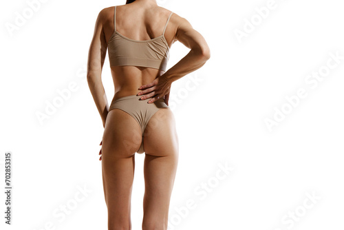 Cropped back view image of slim female body, buttocks in beige cotton underwear over white studio background. Anti-cellulite care, massage. Concept of female beauty, body and skin care, sport, health