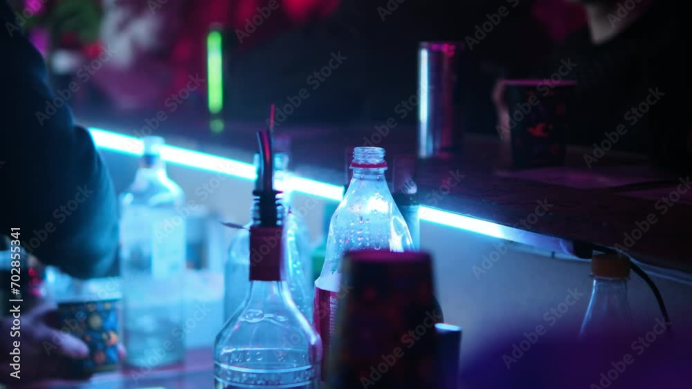 The bartender pours an alcoholic beverage into a paper glass and places it on the bar counter. Selective focus. The bartender pours an alcoholic beverage into a paper glass and places it on the bar counter. Selective focus.