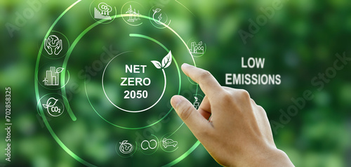 Hand points to a touchscreen with the word Net Zero and an icon against a green background. Concept, goal, zero greenhouse gas emissions. and a long-term climate-neutral strategy. photo