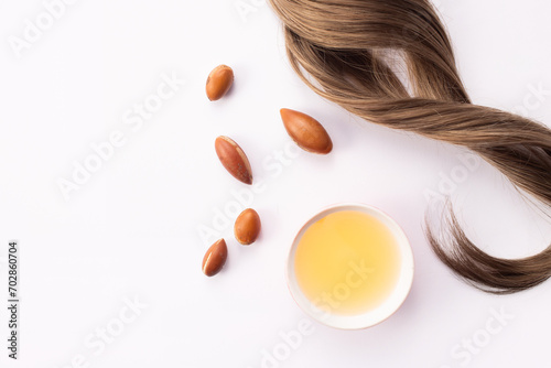 Hairloss concept. Argan seeds, oil and hair isolated on a white background photo