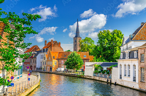 Sint Annarei water canal of Reie river, old buildings on embankment in Brugge old town, Bruges city historical centre, Saint Anna Church tower spire, West Flanders province, Flemish Region, Belgium photo