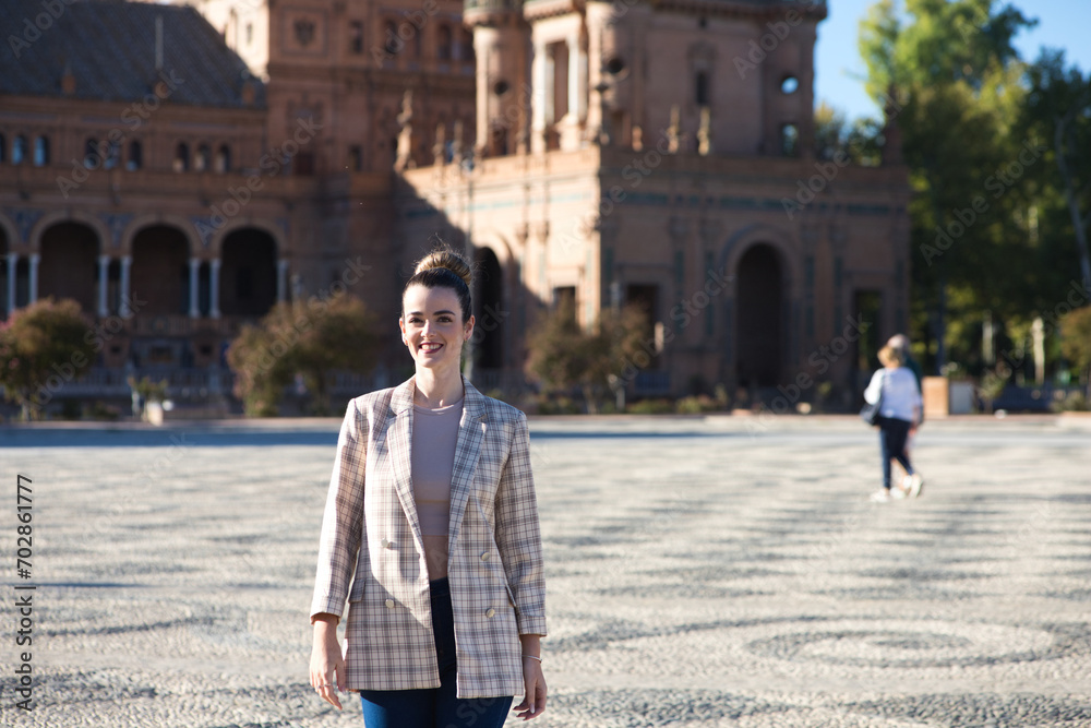 Obraz premium Young and beautiful woman in casual clothes is visiting the famous Plaza de Espana in Seville. The woman enjoys travelling around the old european city. Holiday and travel concept.