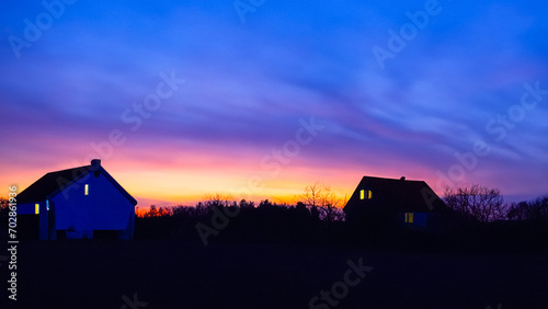 Houses in an area with grass while it is dark with a twilight sky