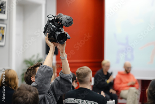 Cameraman shooting people from above with a professional video camera at the conference