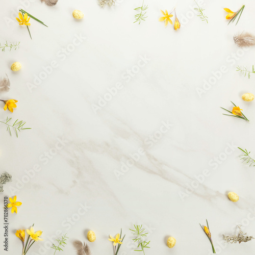 Background frame of spring yellow flowers, Easter eggs on marble background. Minimal Easter concept